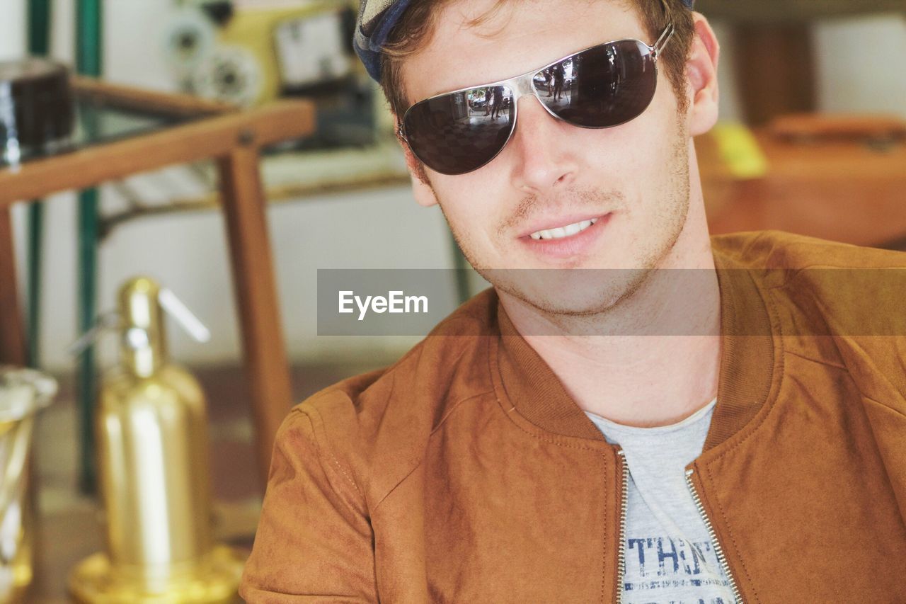 Close-up of young man wearing sunglasses and brown jacket