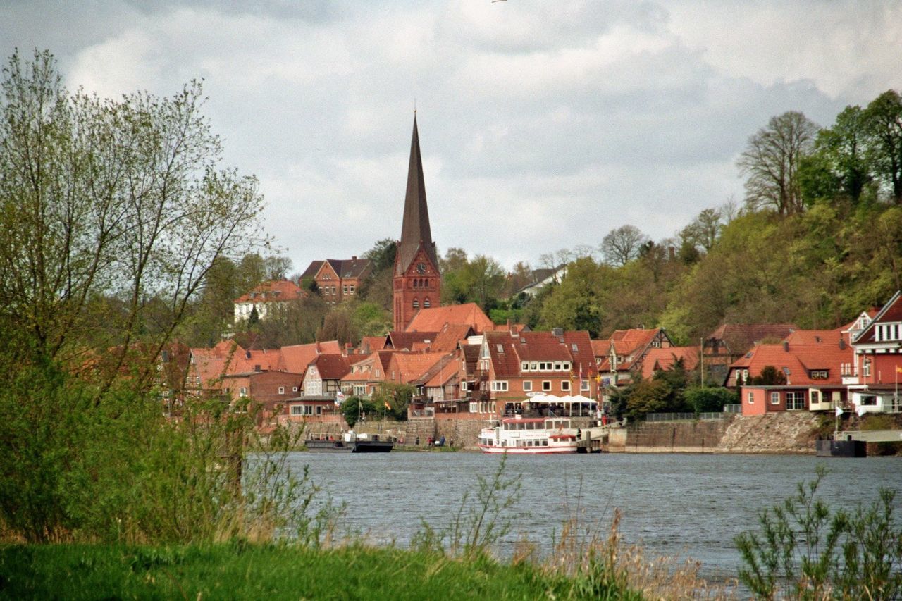 HOUSES BY RIVER AND TOWN AGAINST SKY