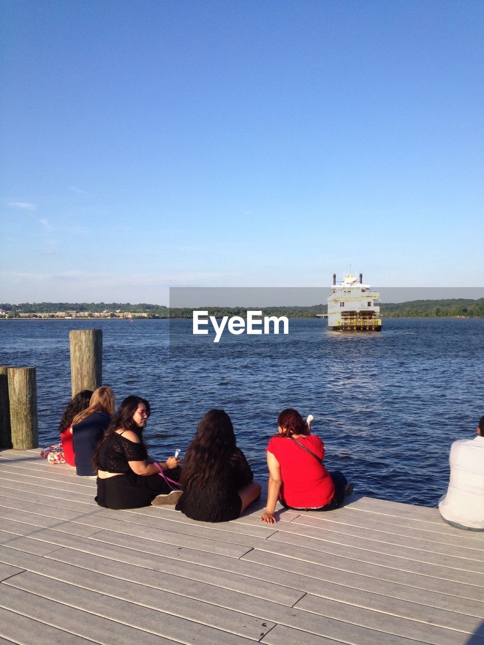 REAR VIEW OF WOMEN SITTING ON THE SEA