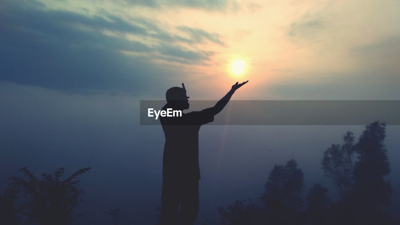 Silhouette man standing against sky during sunrise