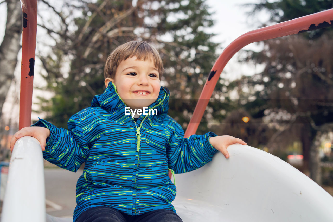 Cute boy playing on slide at playground