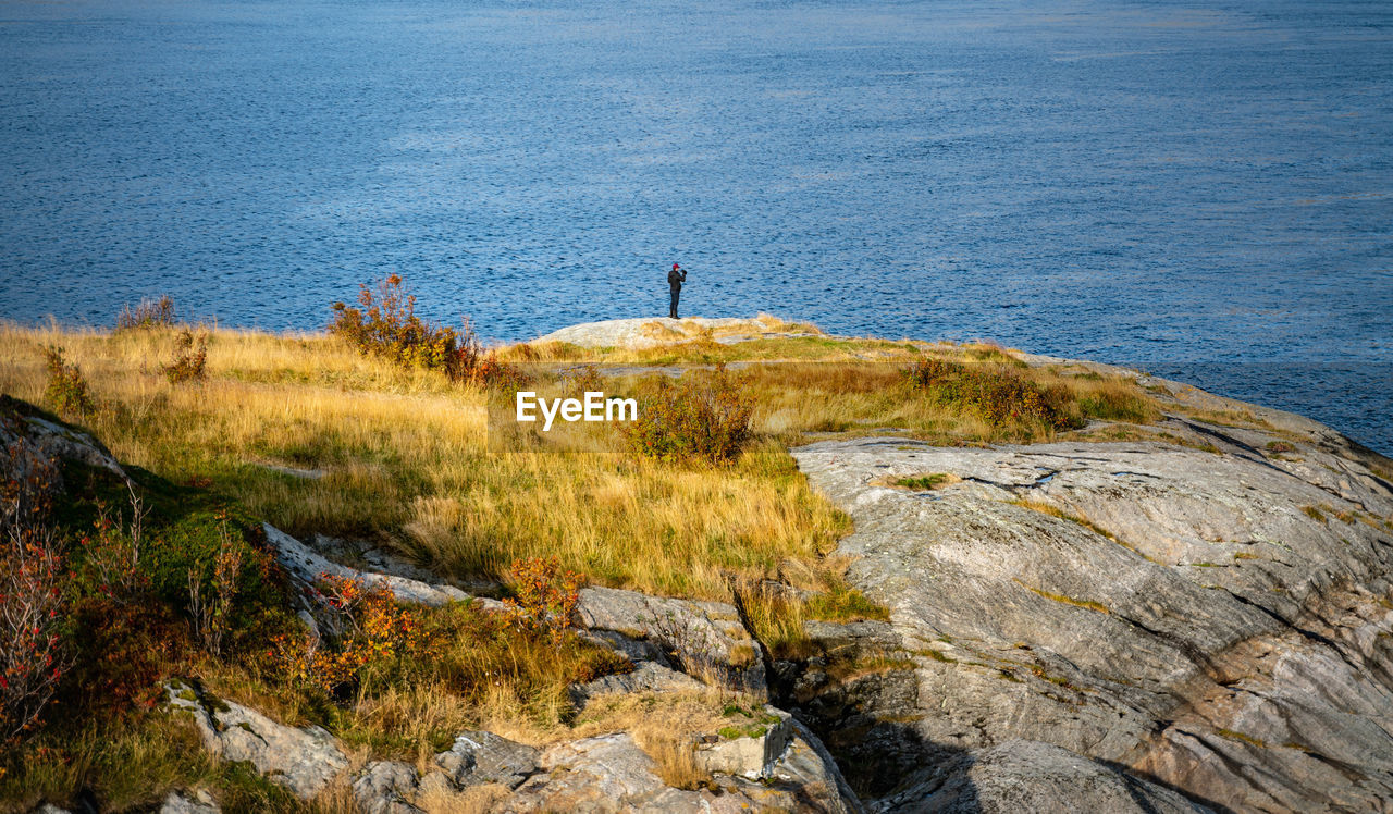 Man standing on rock formation against sea