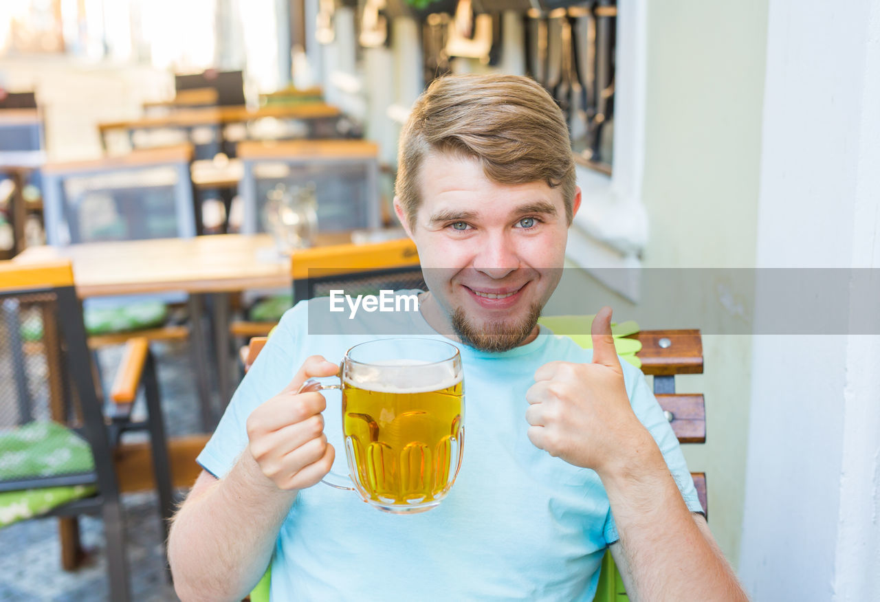 Portrait of smiling man holding beer glass at bar
