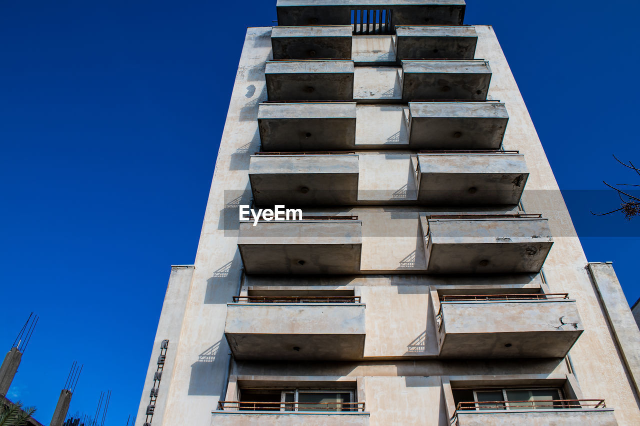 architecture, tower block, sky, built structure, clear sky, blue, low angle view, building exterior, facade, tower, landmark, building, no people, nature, skyscraper, sunny, day, outdoors, industry, city, construction industry, house, residential district, window, brutalist architecture, staircase, sunlight, apartment