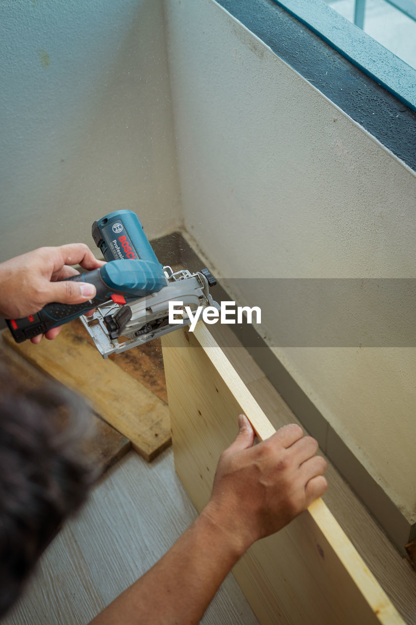 HIGH ANGLE VIEW OF MAN WORKING IN WOOD