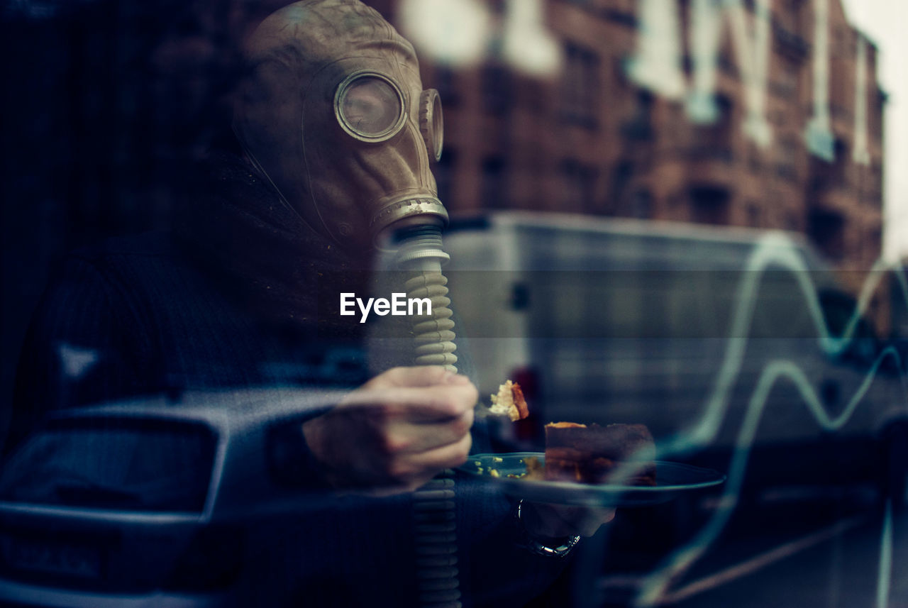 Man wearing gas mask seen through window