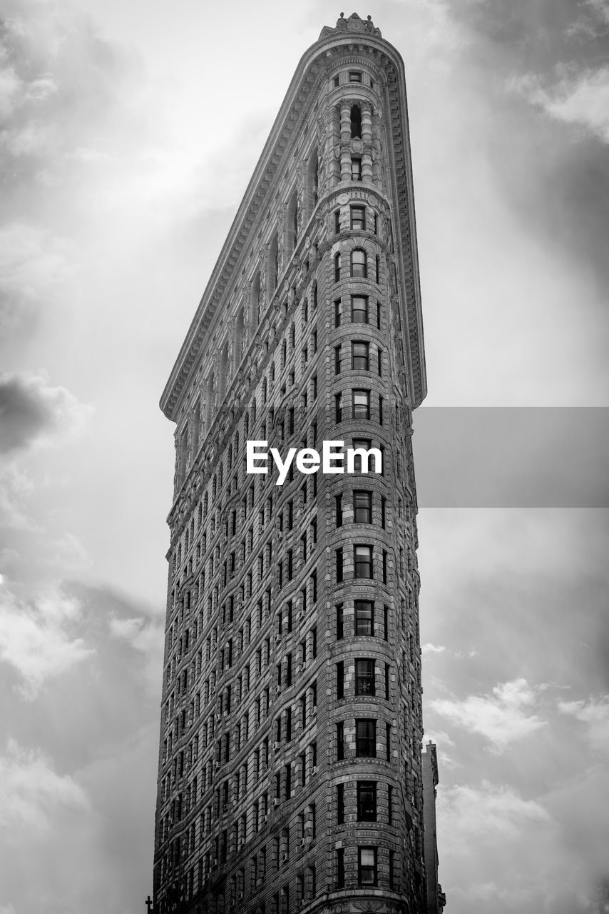 Low angle view of flatiron building against cloudy sky
