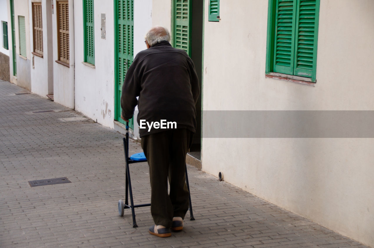 Rear view of pensioner walking on footpath