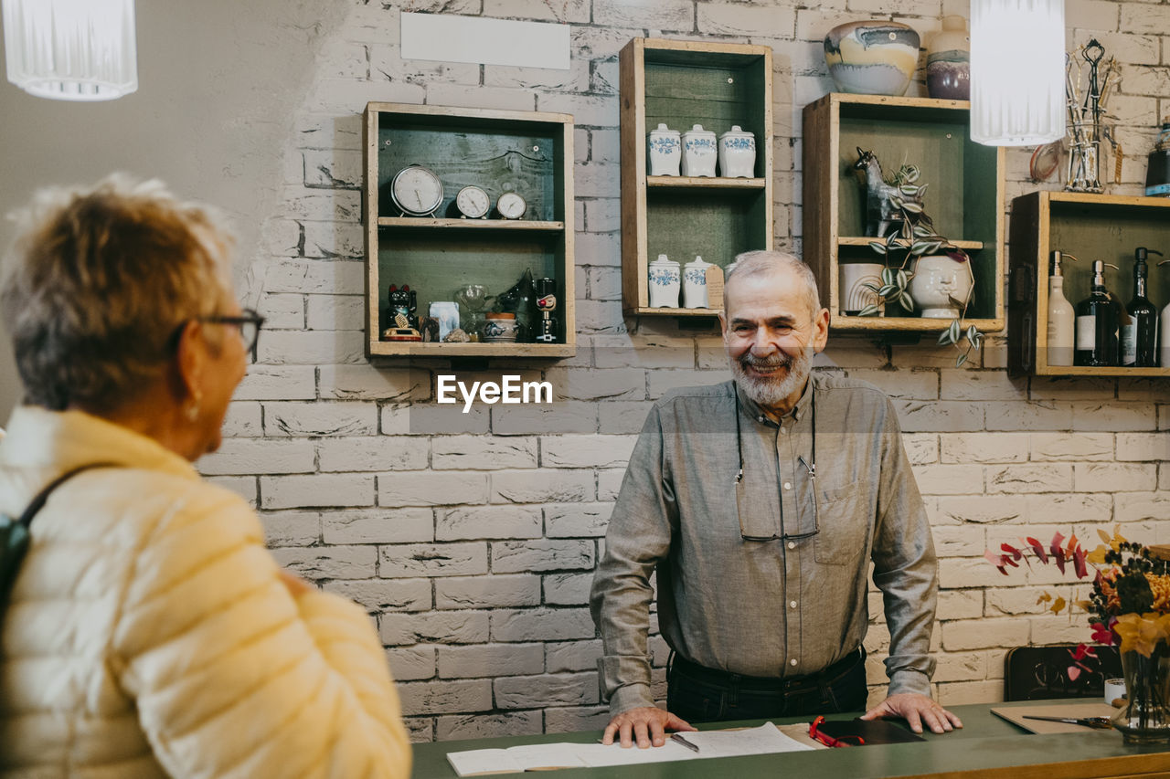 Happy senior owner greeting customer at home decor store