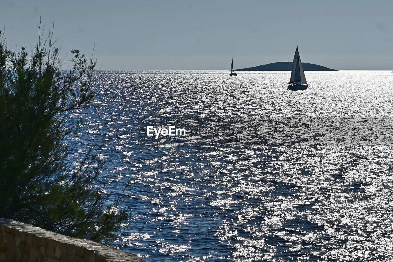 water, sea, nautical vessel, sky, nature, transportation, ship, sailboat, beauty in nature, horizon, vehicle, ocean, boat, environment, scenics - nature, travel, no people, tranquility, shore, sailing, tranquil scene, mode of transportation, day, travel destinations, architecture, reflection, outdoors, sunlight, blue, winter, tourism, horizon over water, holiday, landscape, non-urban scene, beach, sunny, coast, clear sky, idyllic, watercraft, built structure, vacation, wave, wind