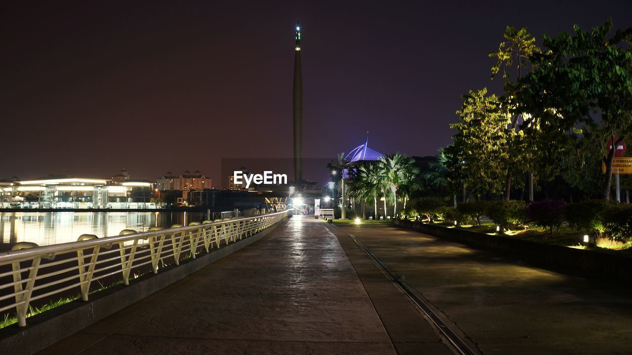 Street amidst illuminated city against sky at night