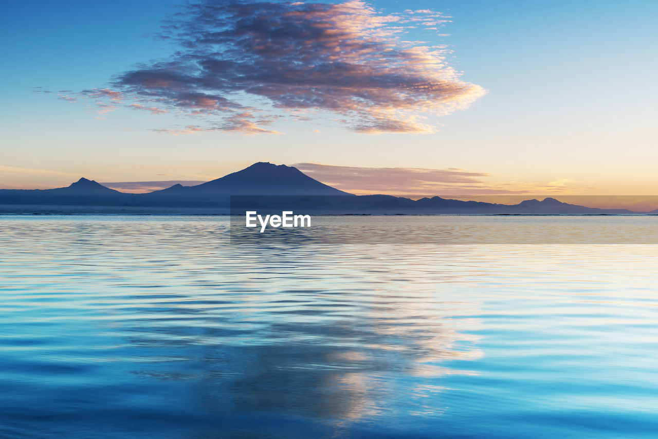 SCENIC VIEW OF SEA BY SILHOUETTE MOUNTAINS AGAINST SKY