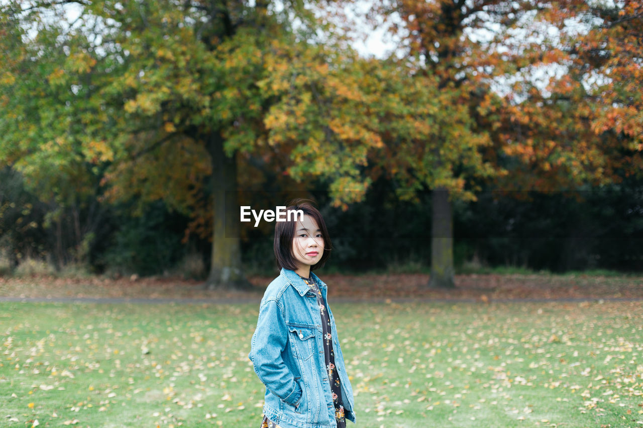 Portrait of woman standing against trees