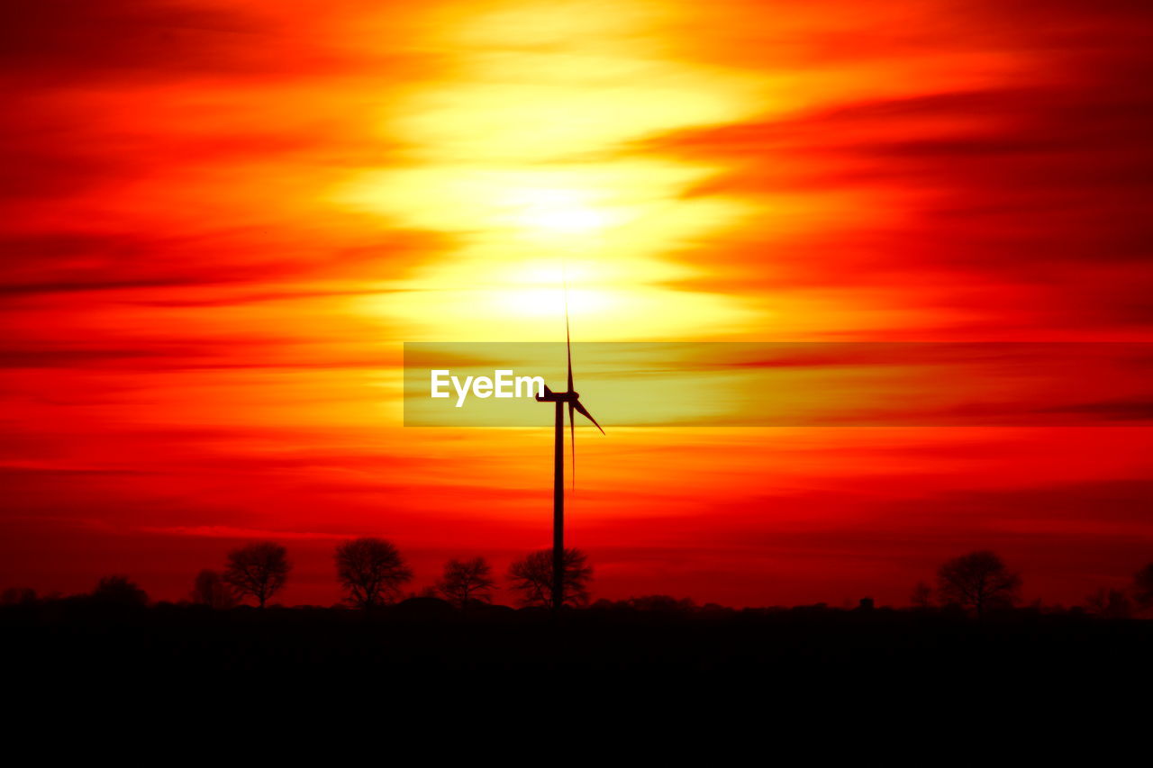 SILHOUETTE OF WIND TURBINE AGAINST ORANGE SKY