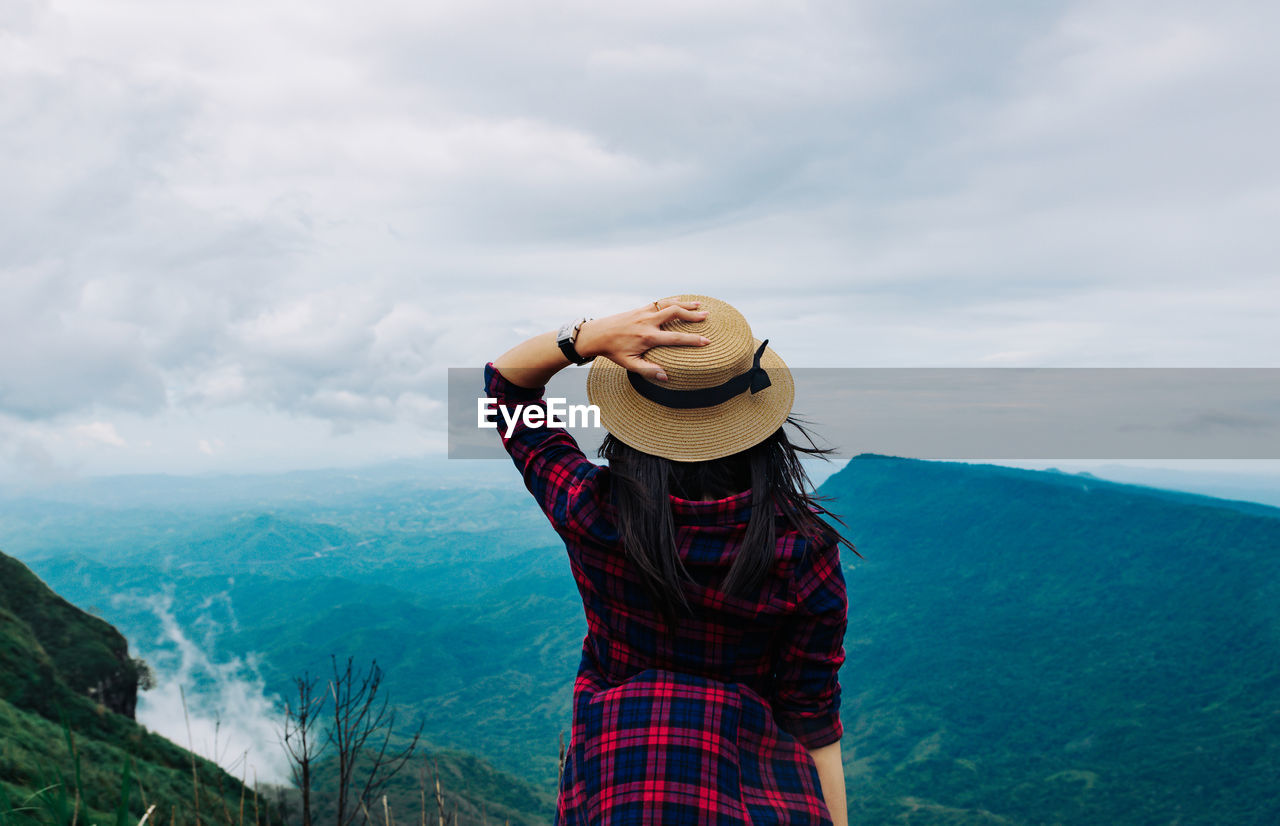 Rear view of woman standing on mountain against sky