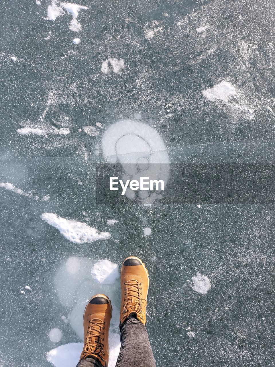 Feet of a person standing on the ice of a frozen lake