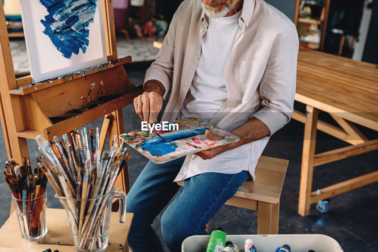 Midsection of man holding painting equipment