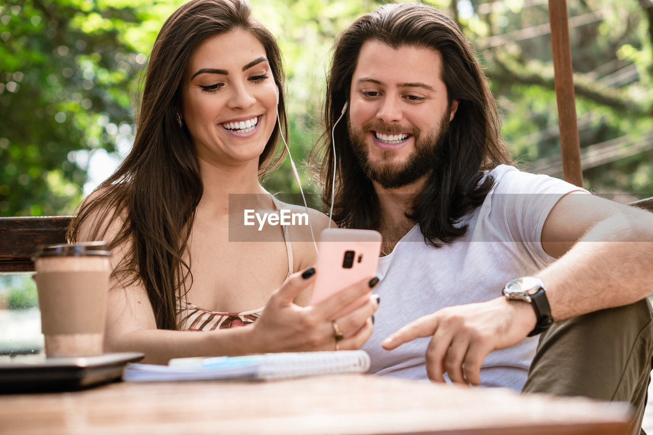 Smiling couple using mobile phone outdoors