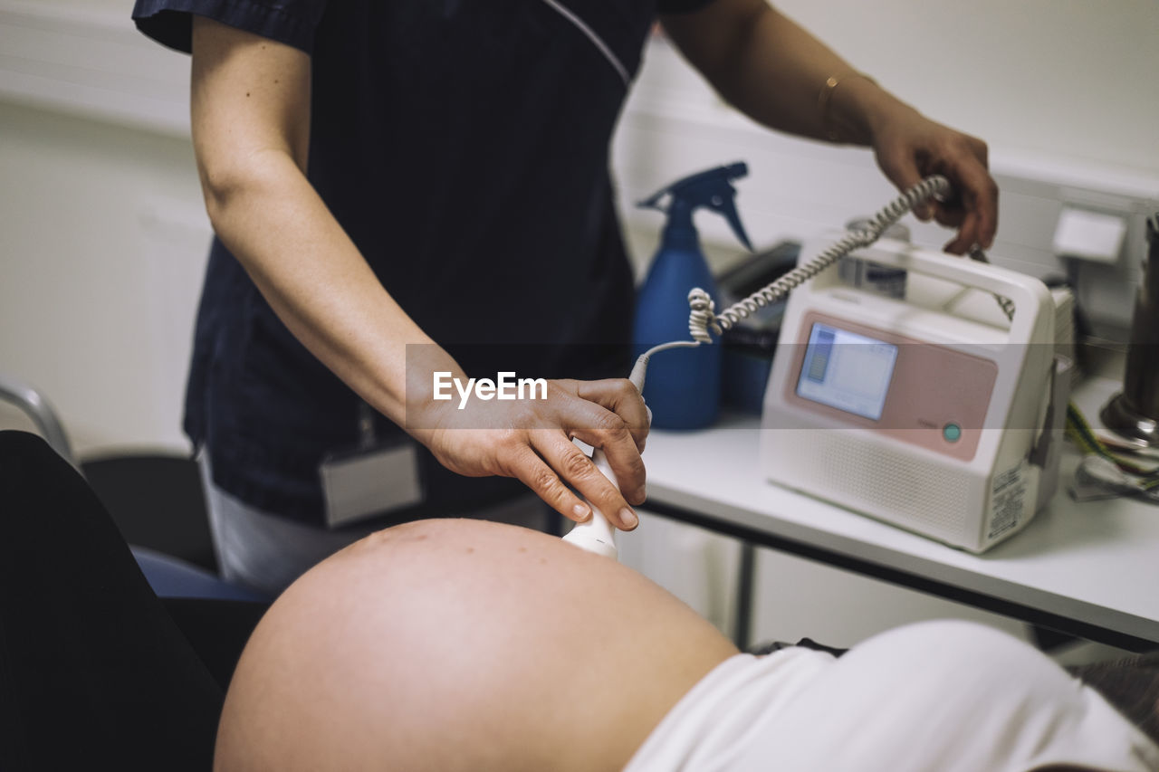 Female healthcare expert doing ultrasound of pregnant woman in medical clinic