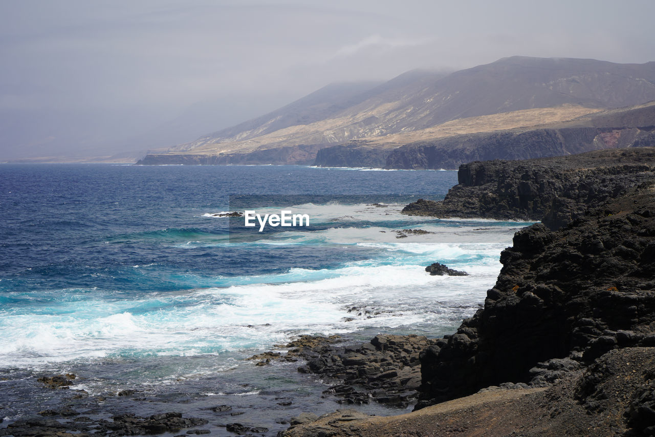 SCENIC VIEW OF SEA BY MOUNTAINS AGAINST SKY