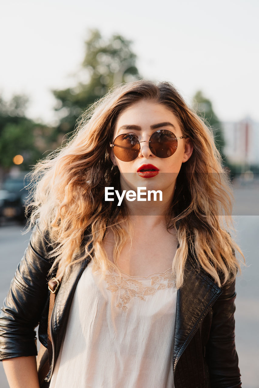 Portrait of young woman wearing sunglasses against sky