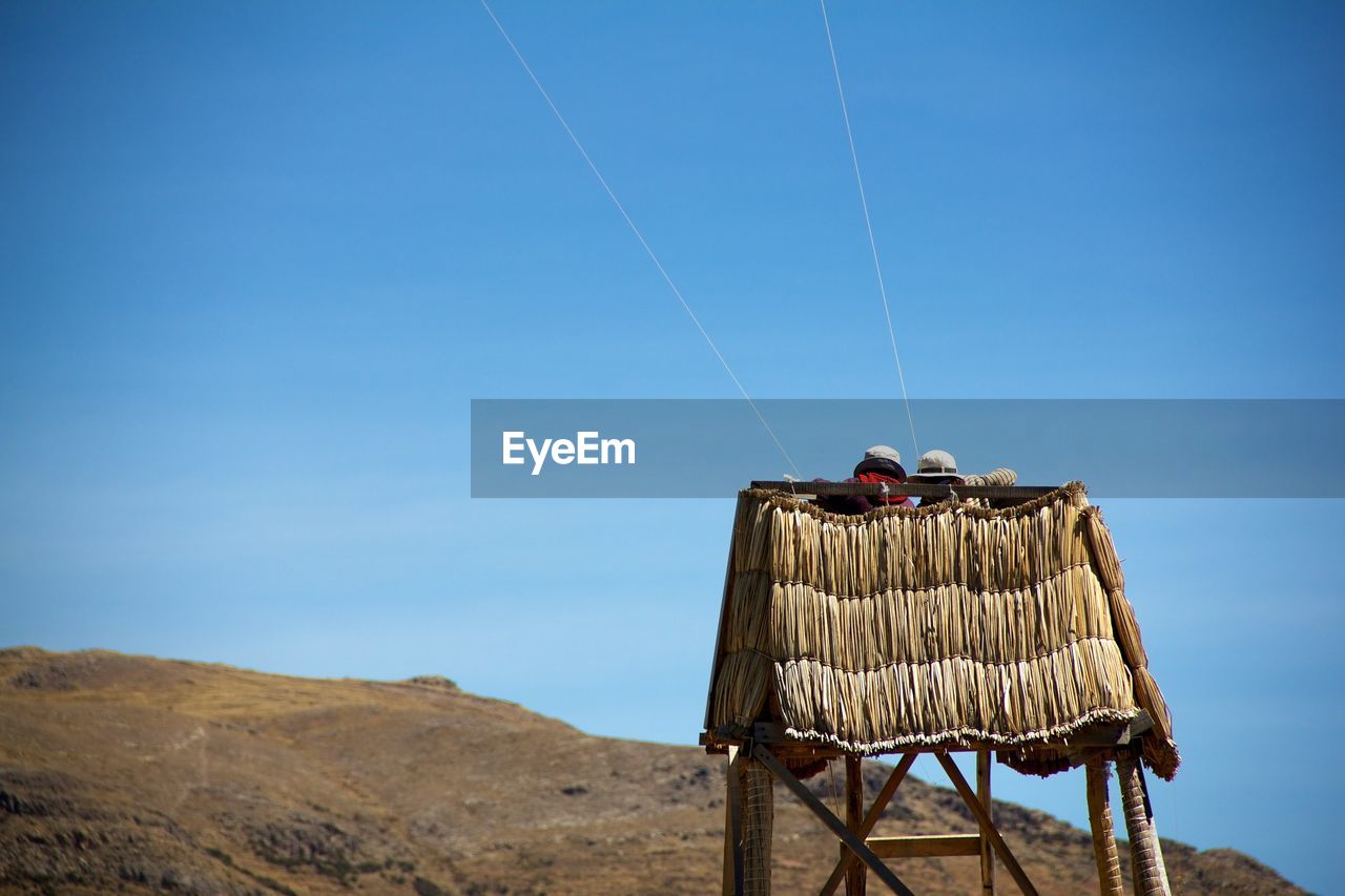 Low angle view of people on tower against blue sky