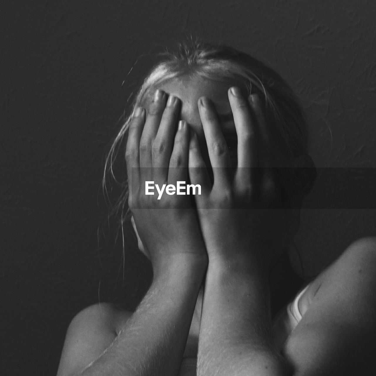 Low angle view of young woman covering face against ceiling