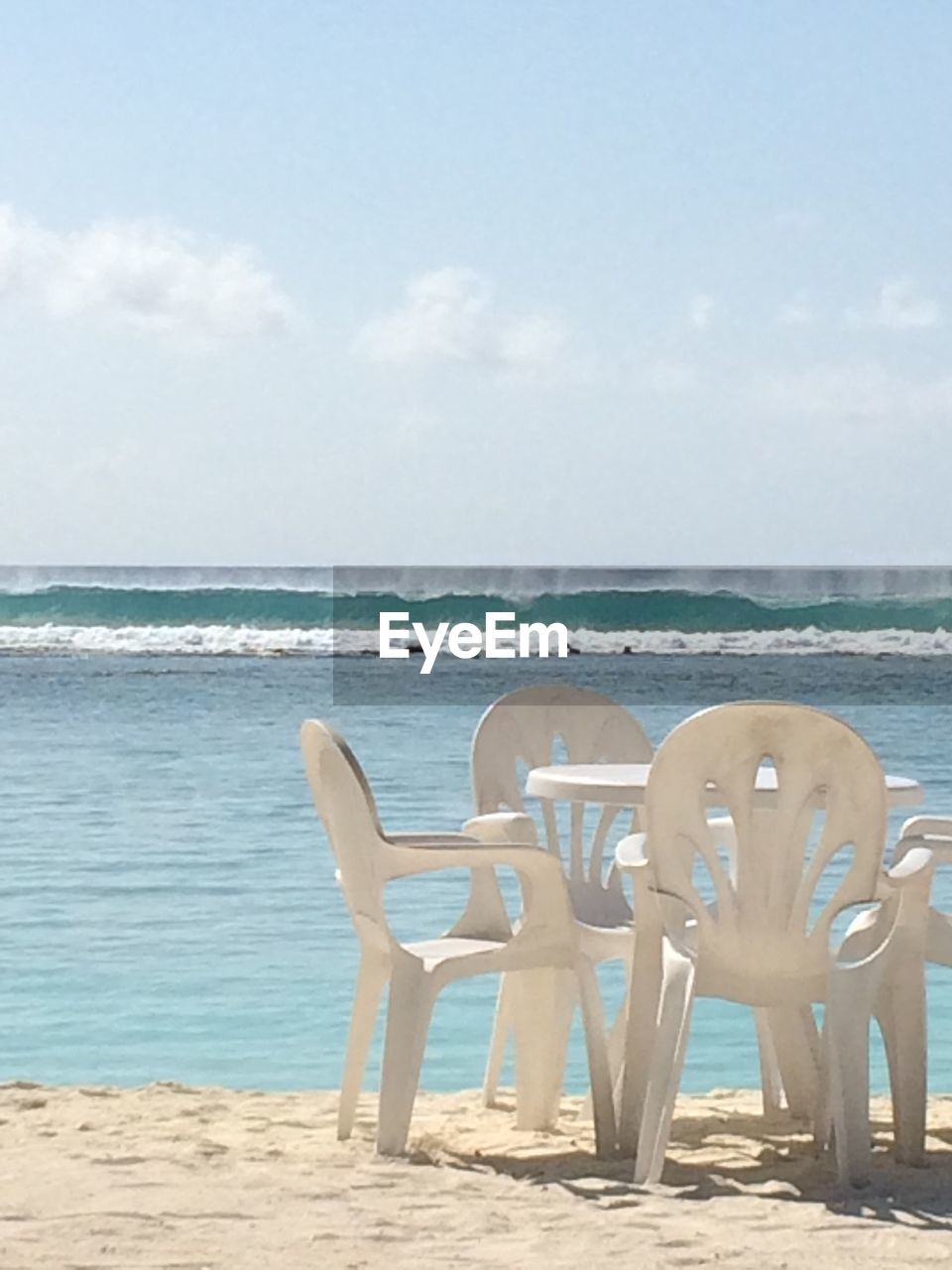 LOUNGE CHAIRS ON BEACH AGAINST SKY