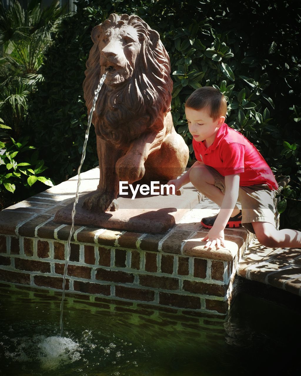 FULL LENGTH OF BOY STANDING ON SCULPTURE