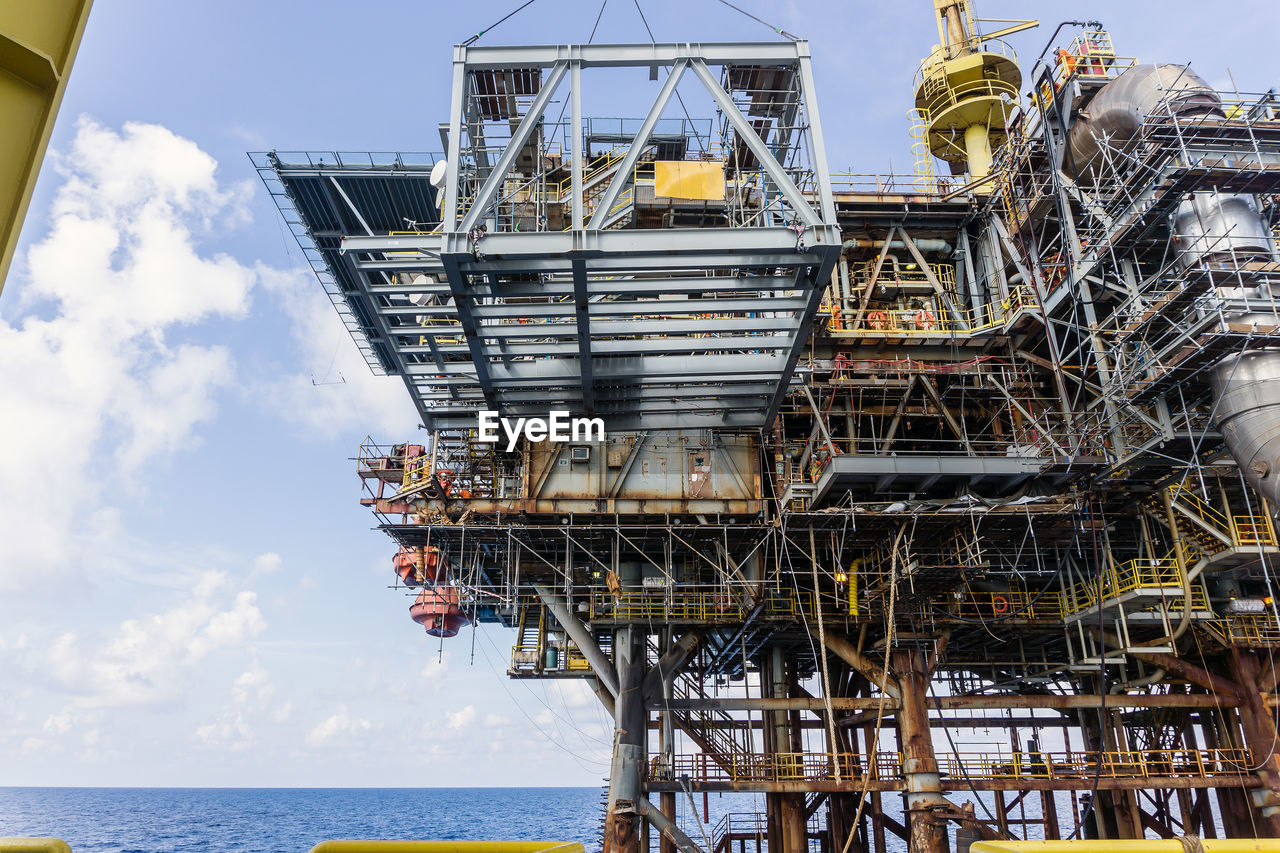 Low angle view of oil production platform against sky during an installation of a structure frame