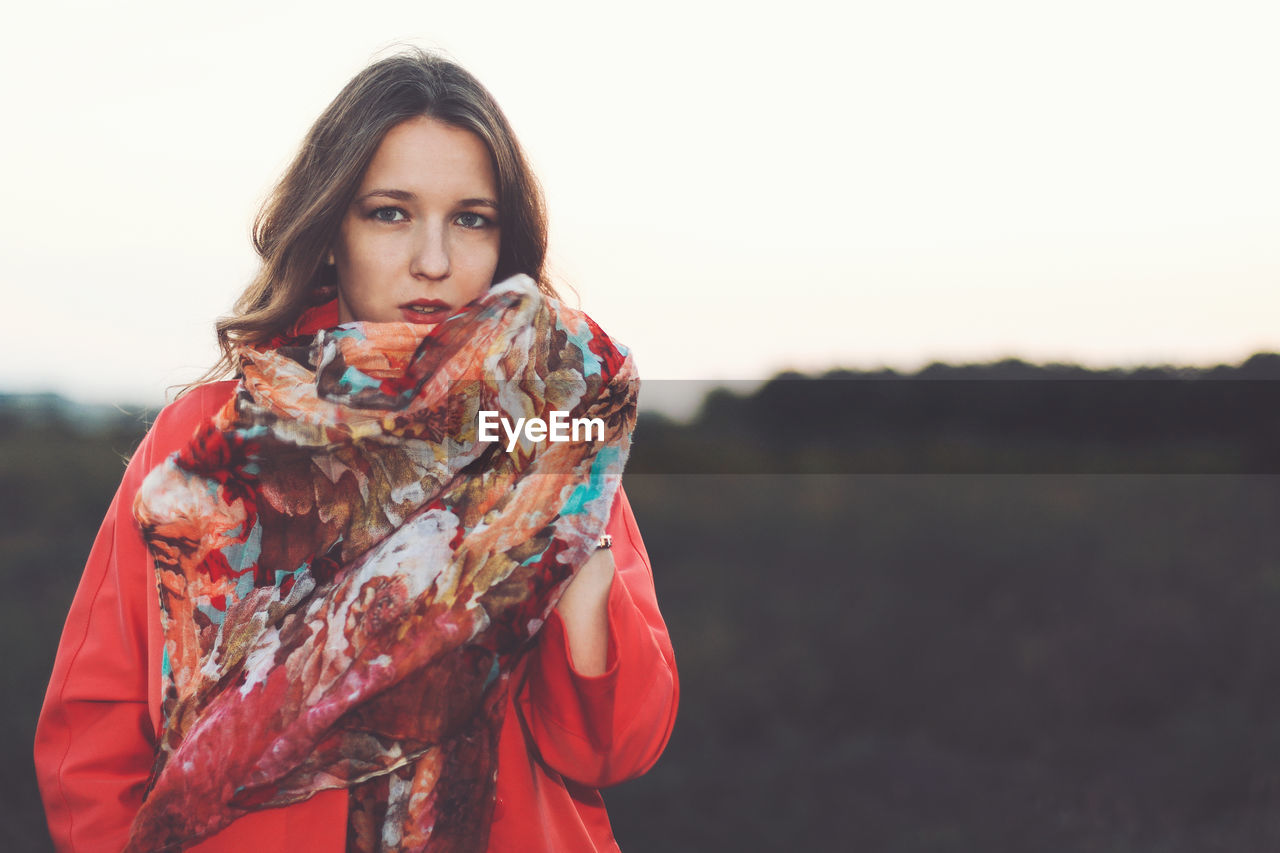 Portrait of beautiful young woman standing on field