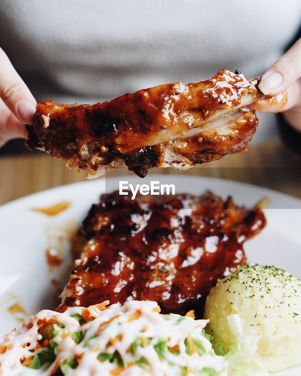 Midsection of woman holding meat rib at table