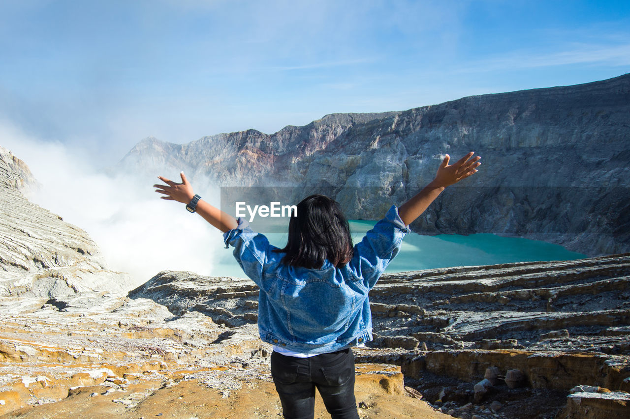 Rear view of woman with arms outstretched standing on mountain