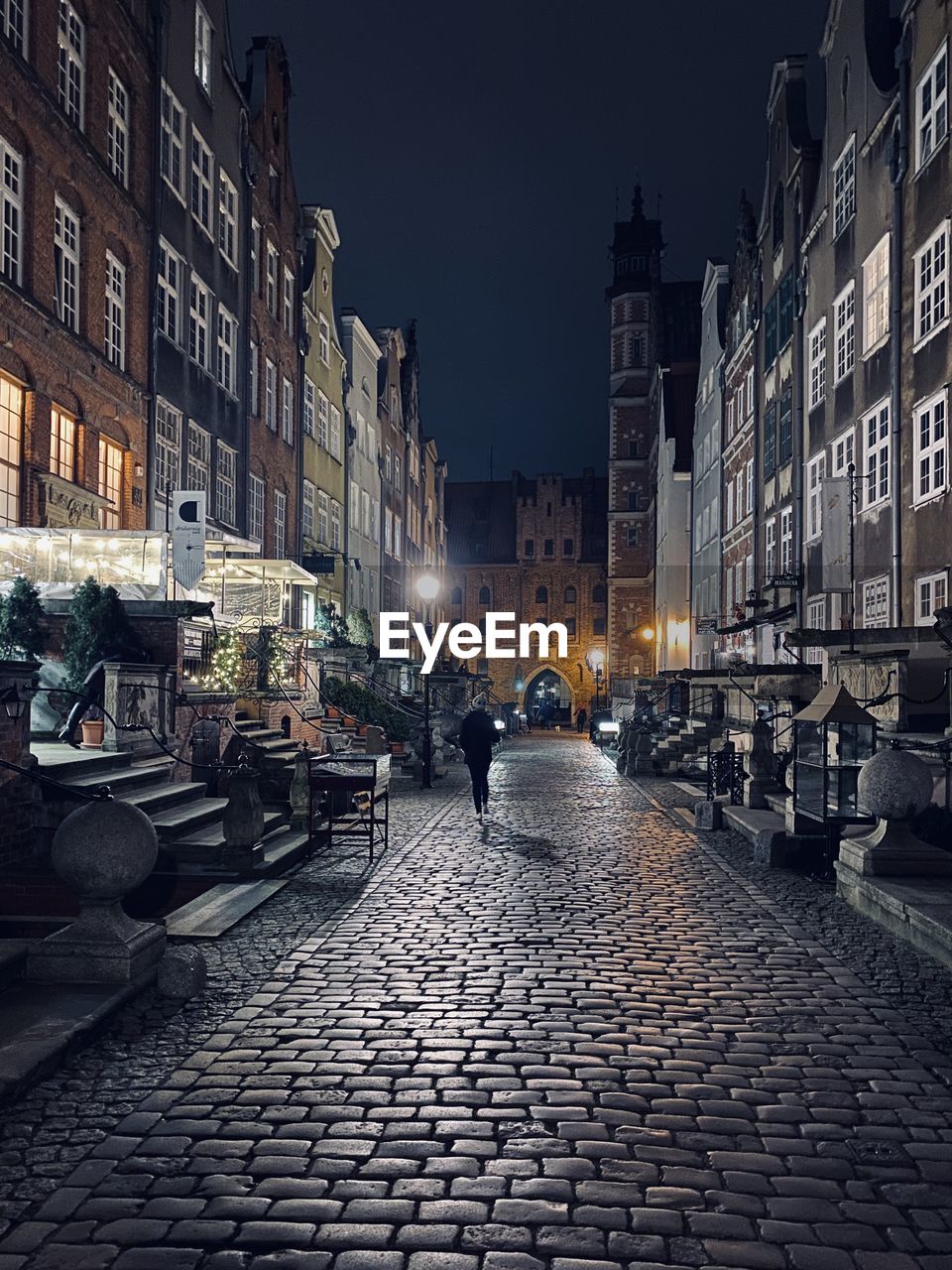 People on street amidst illuminated buildings in city at night