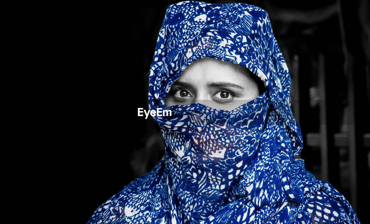 Close-up portrait of woman in hijab against black background