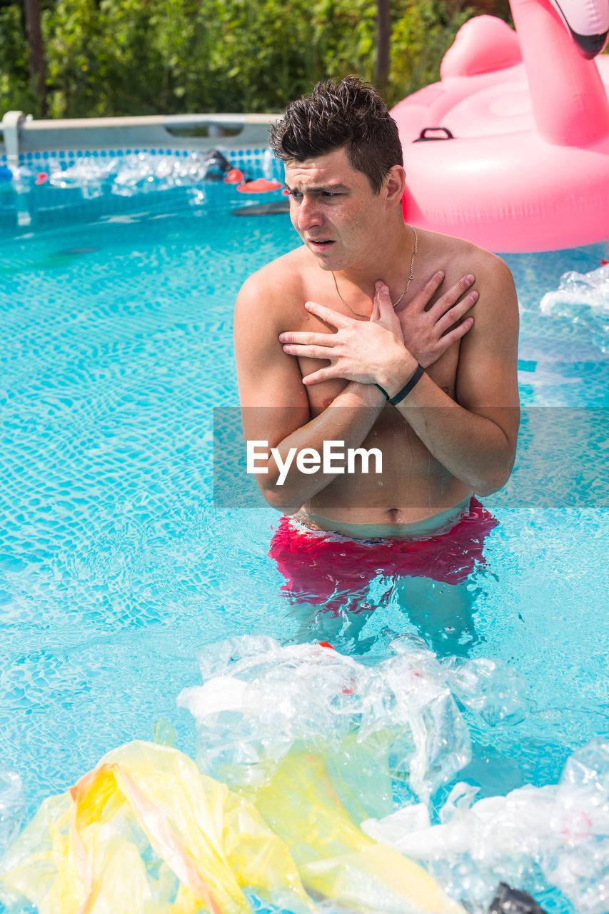 MIDSECTION OF MAN SWIMMING IN POOL