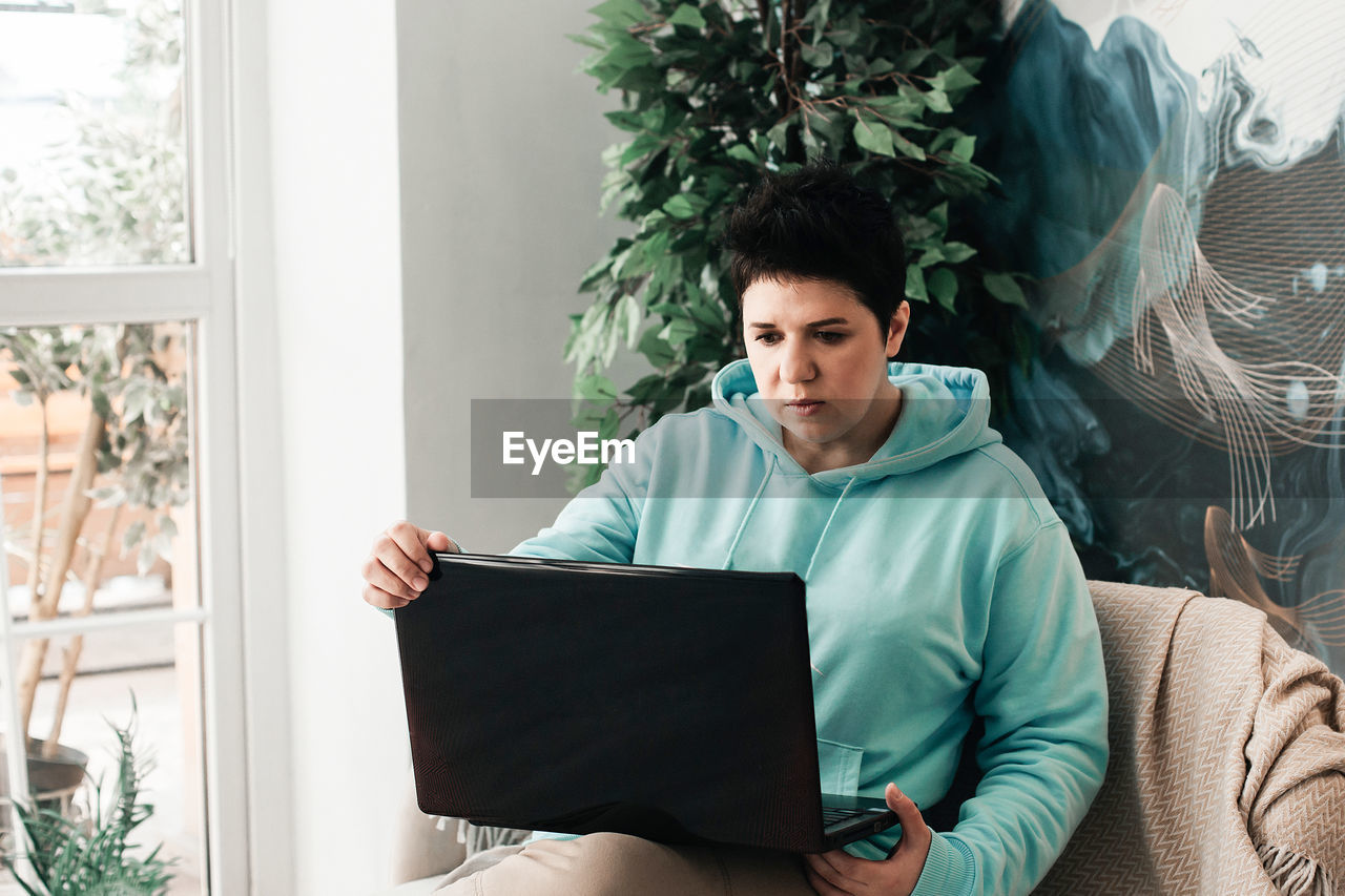 YOUNG MAN USING PHONE WHILE SITTING ON SOFA