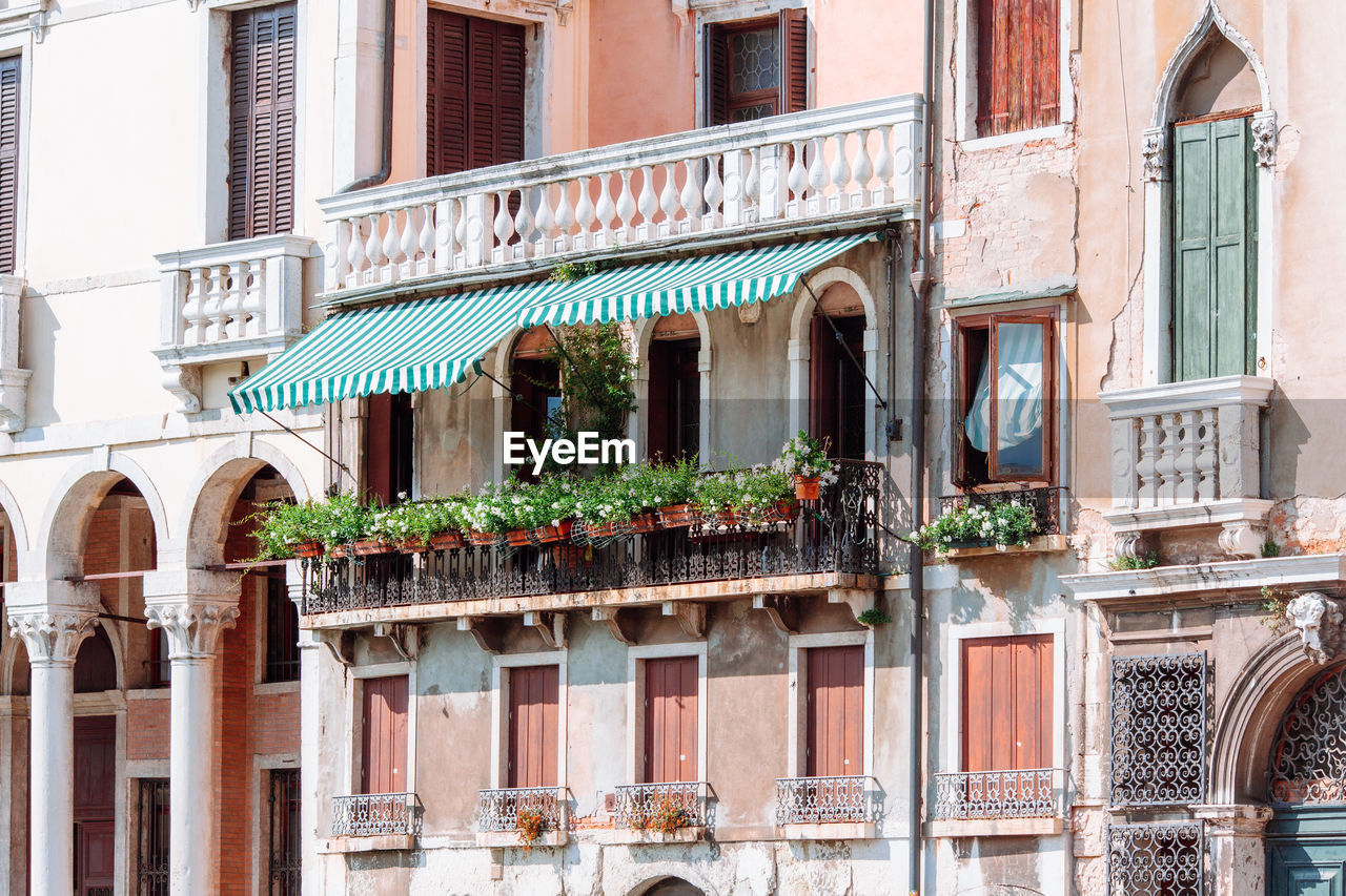 Large balcony with many flower pots on it. facade of one of the old houses in venice on grand canal