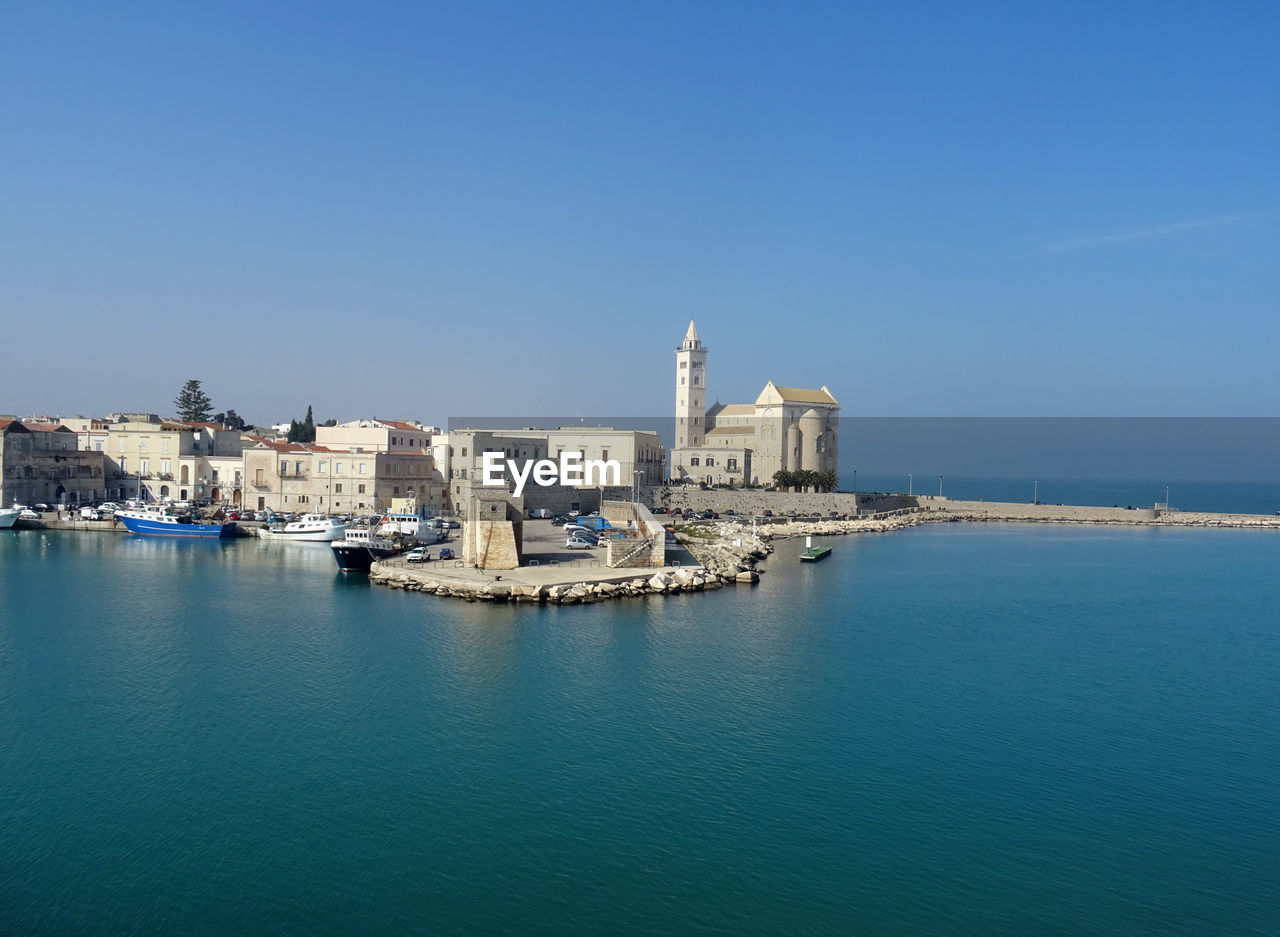 View of buildings by sea against blue sky