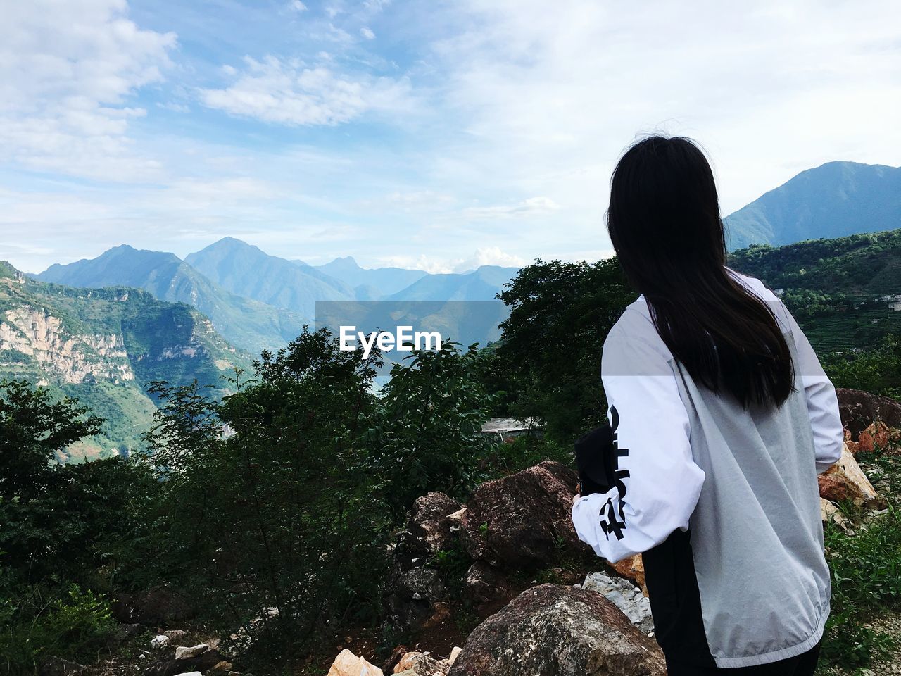 Rear view of woman standing on mountain against sky