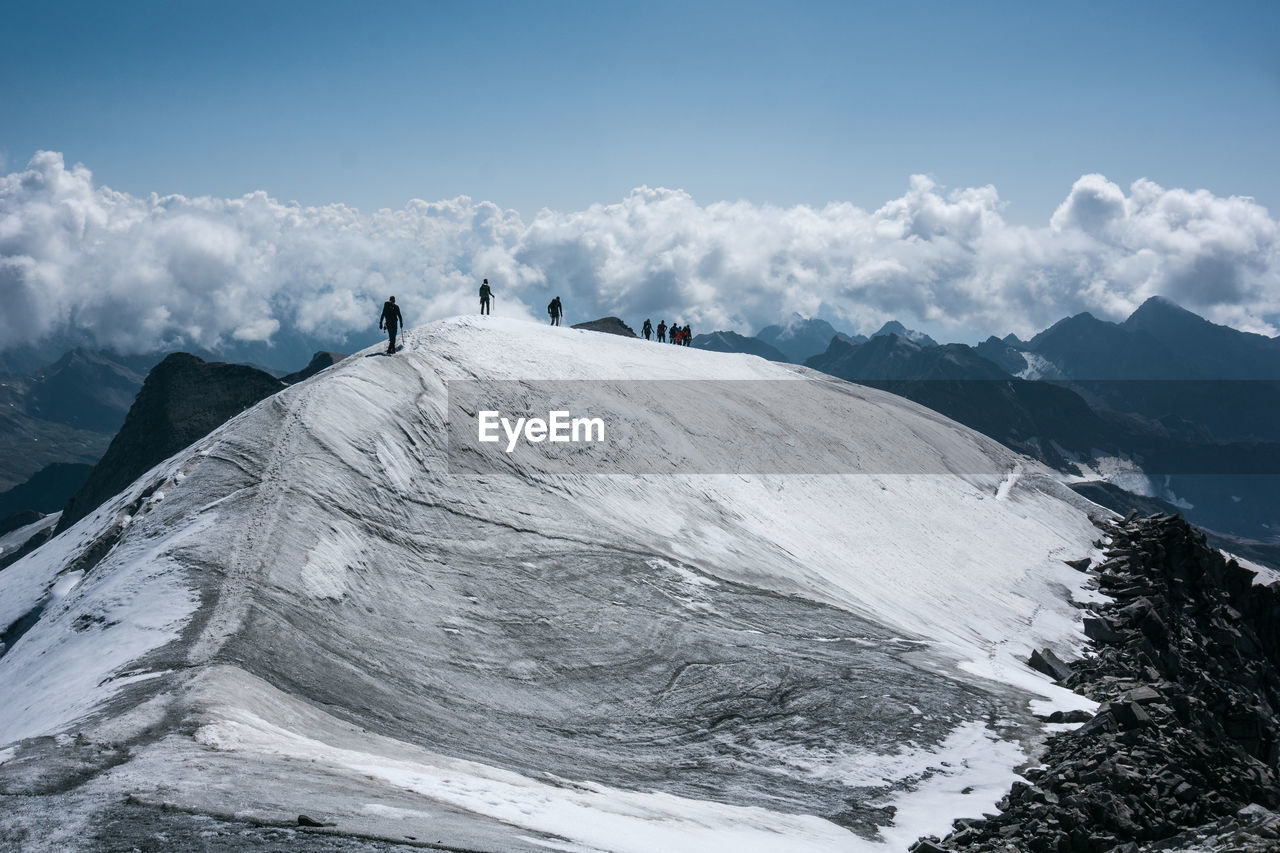 PEOPLE ON SNOWCAPPED MOUNTAINS AGAINST SKY