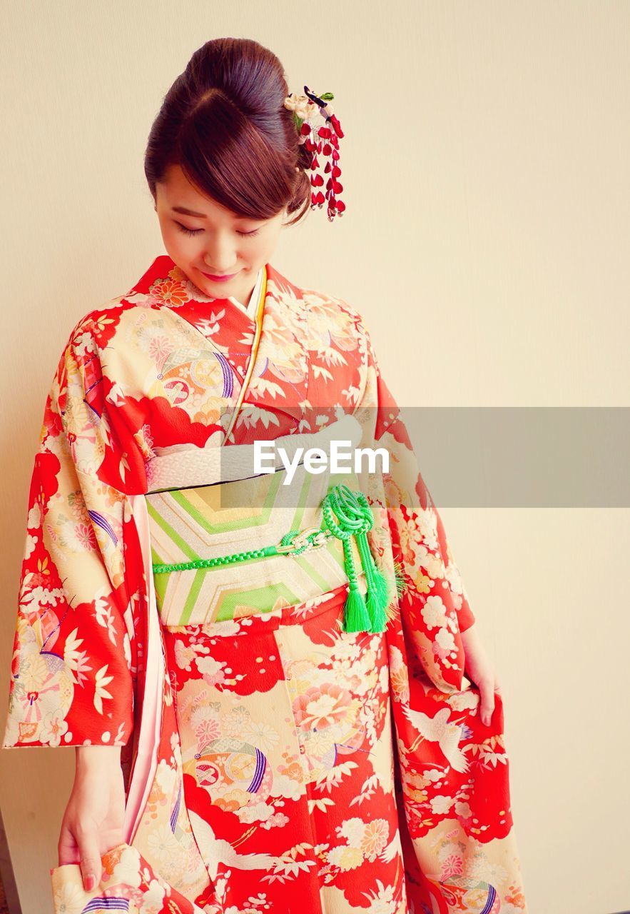 Young woman wearing kimono against beige wall