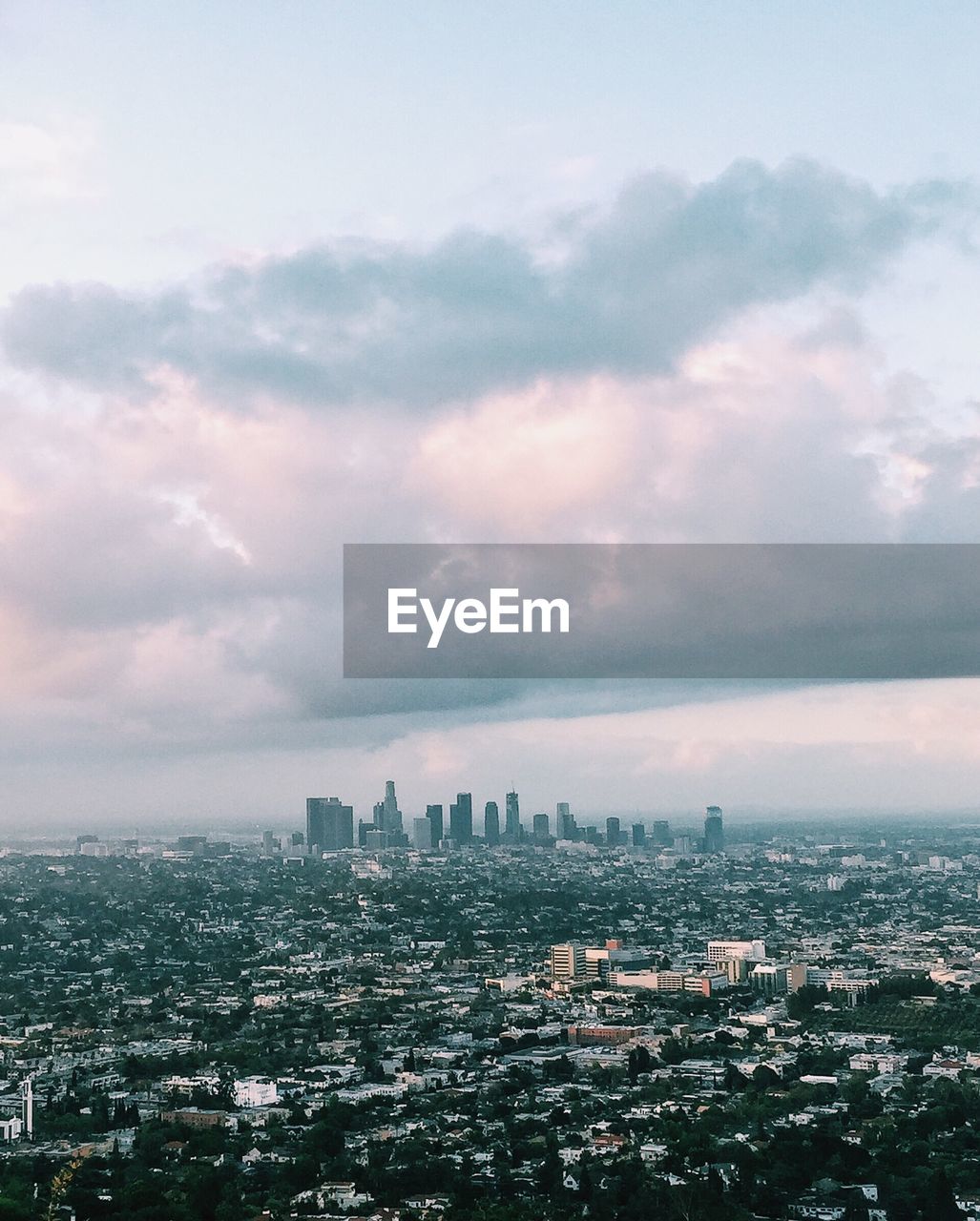 Cityscape against cloudy sky during sunset