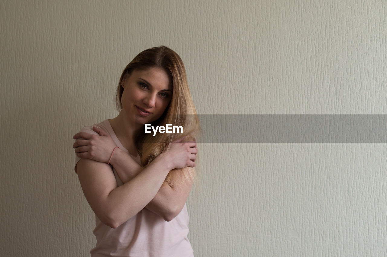 Portrait of smiling woman standing against wall