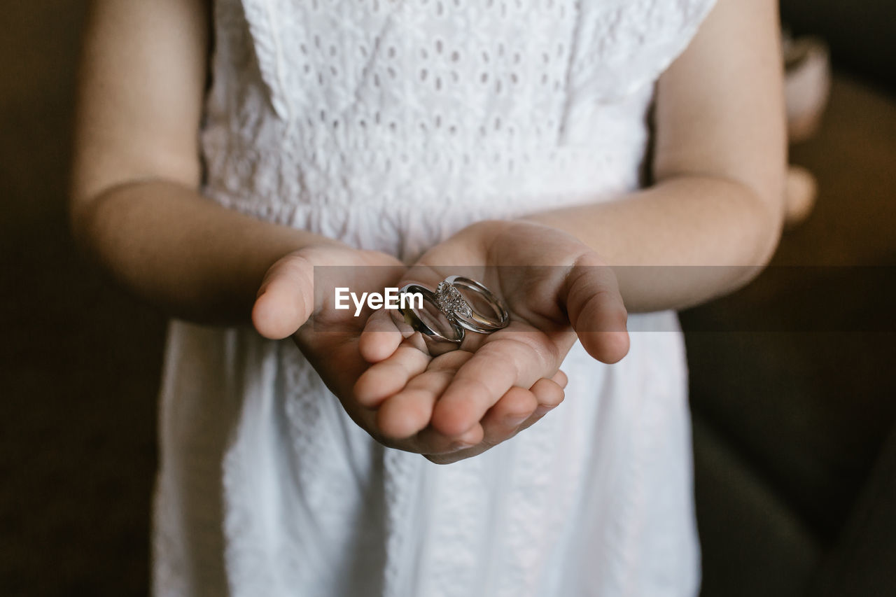 Midsection of flower girl holding wedding rings