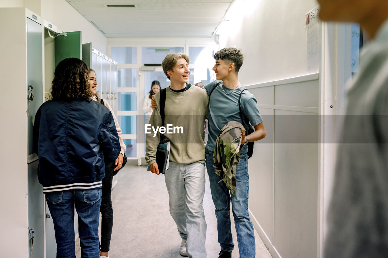 Smiling teenage boys walking together in school corridor