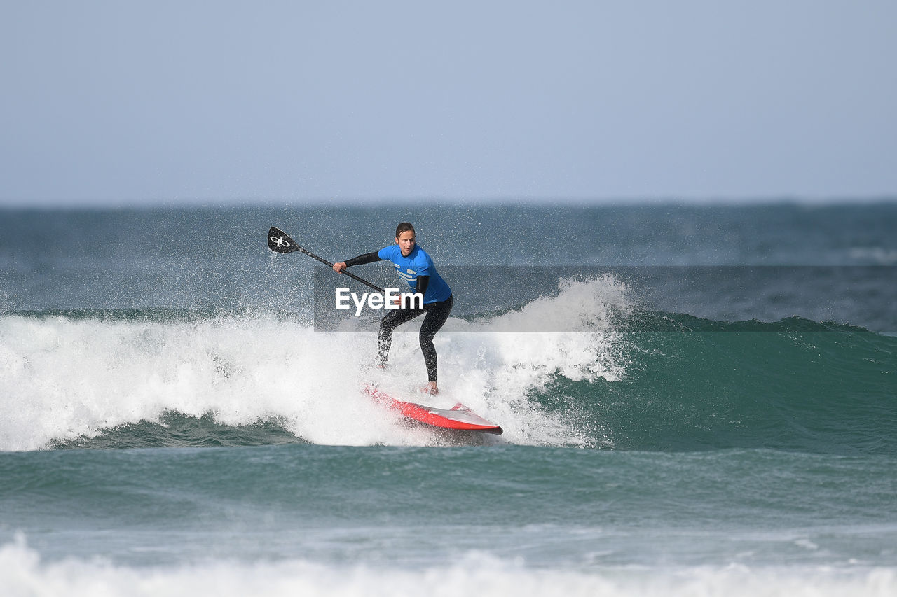 FULL LENGTH OF MAN SURFING ON SEA