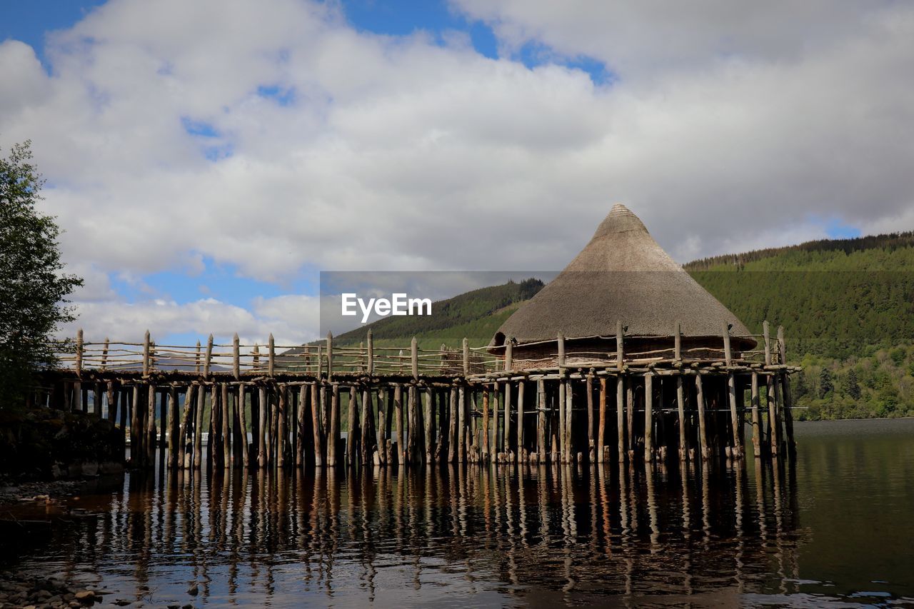 WOODEN POST IN LAKE AGAINST SKY