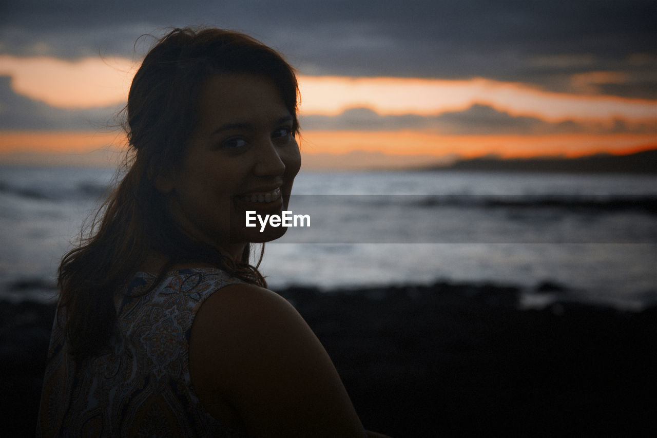 Portrait of smiling young woman at beach during sunset