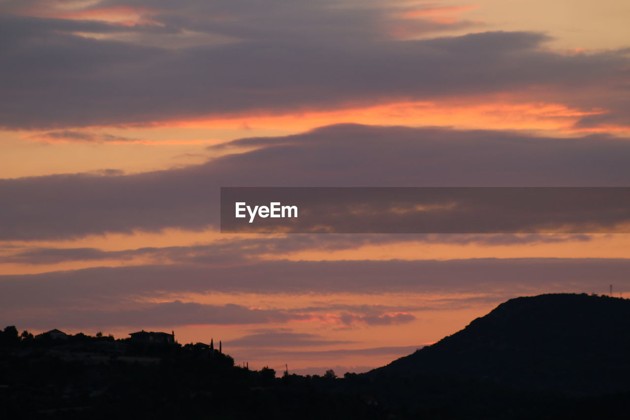 Silhouette landscape against dramatic sky during sunset